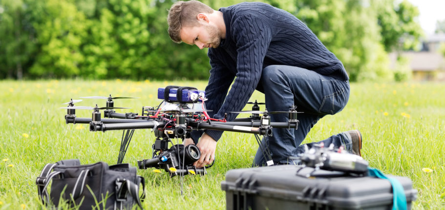 Young Engineer Setting SLR Camera On UAV Helicopter At Park